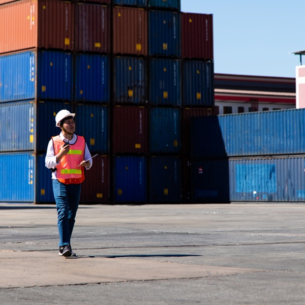 Agent en gilet de sécurité marchant devant des conteneurs empilés illustrant les solutions de containers aménagés