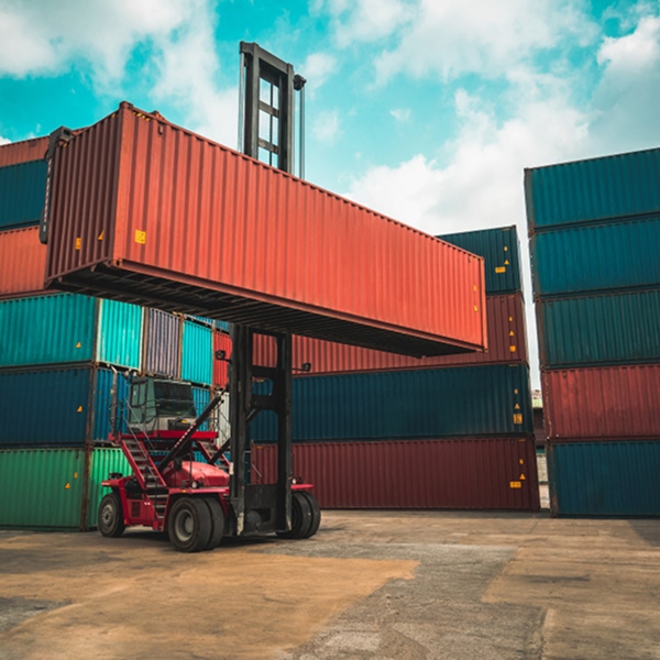 Chariot élévateur déplaçant un conteneur rouge dans un parc de vente pour particuliers à Montréal