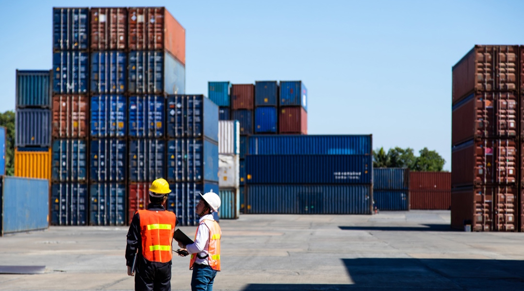 Deux techniciens en gilets de sécurité discutant devant un parc de conteneurs de différentes grandeurs et usages