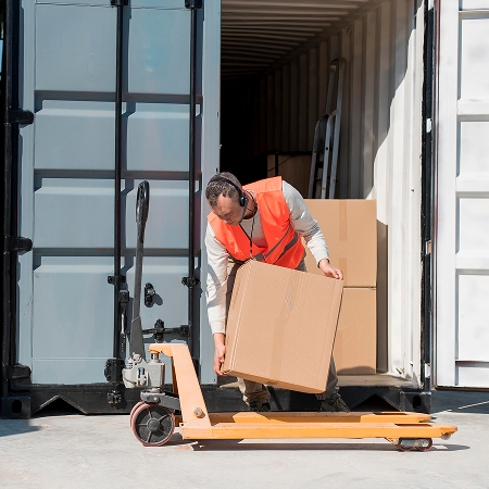 Manutentionnaire déchargeant des boîtes d'un conteneur habitable illustrant la praticité du choix à Lévis