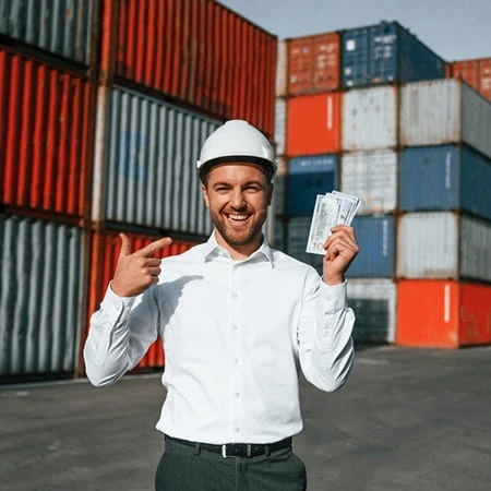 Portrait d'un jeune homme souriant tenant un conteneur devant des conteneurs de transport.